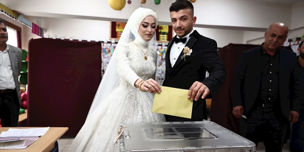 Gelinlik ve damatlıkla oy kullanmaya gelen çift yüzleri güldürdü